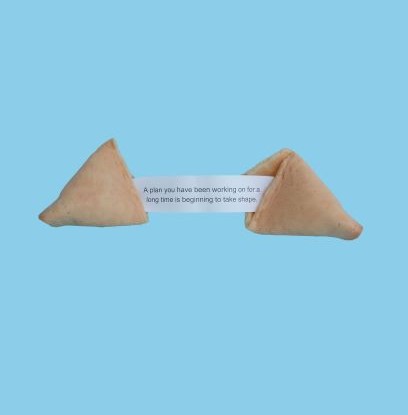 Fortune cookie against blue background. Fortune says "A plan you have been working on is beginning to take shape"