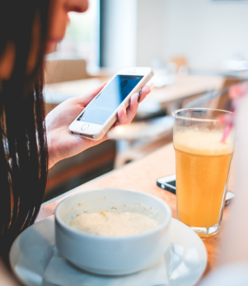 Supply Chain Scene, image of a woman eating and looking at her iphone 