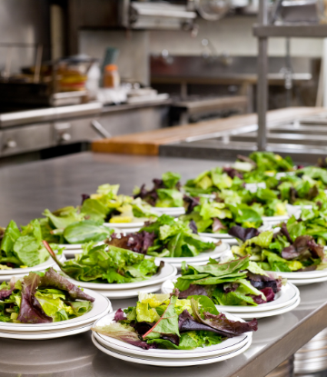 Supply Chain Scene, image of a commercial kitchen with salad plates lined on the counter 