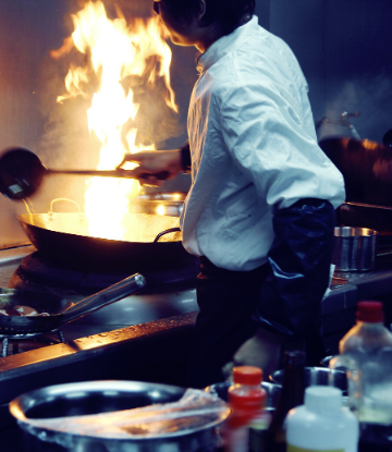 SCS, image of a cook in a commercaial kitching using a wok with high flame 