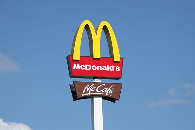 McDonald's sign with McCafe sign below and blue sky above.