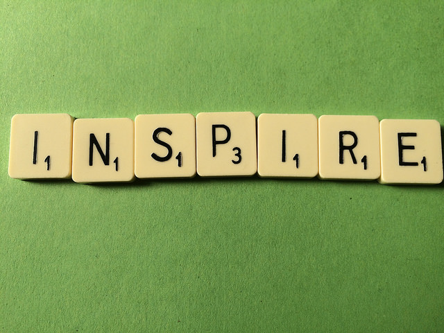 Scrabble tiles that spell "Inspire" on green background.