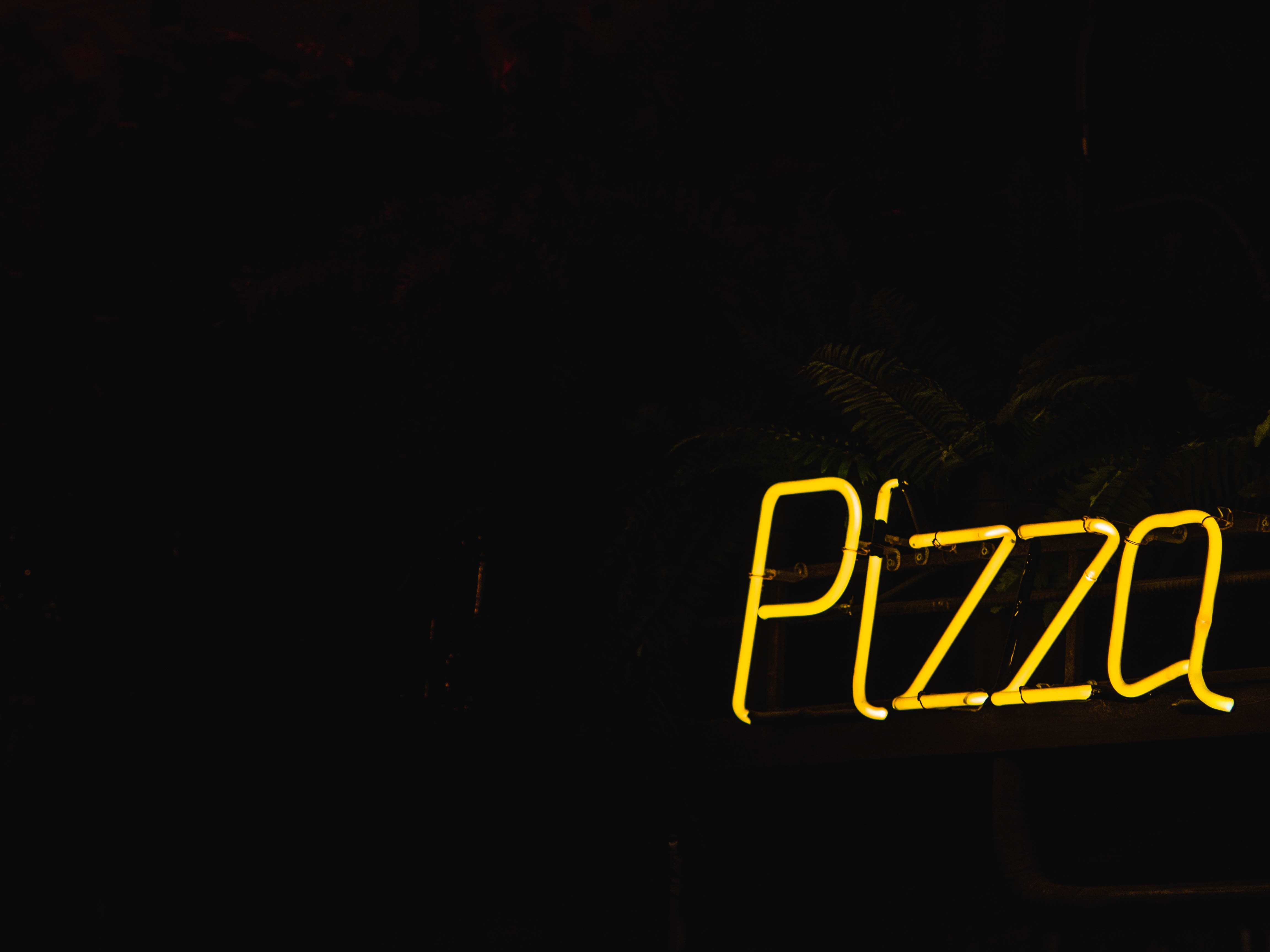 Neon yellow sign that says "Pizza"