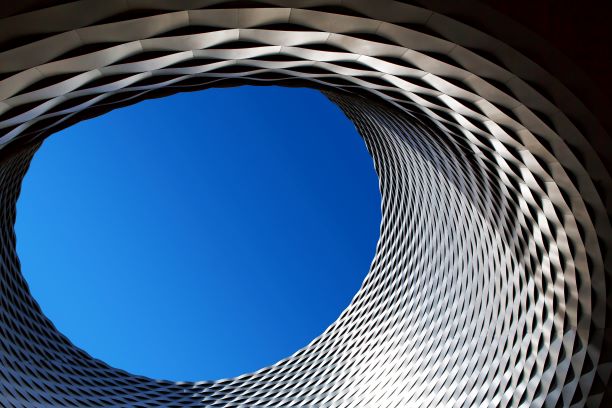 Oval structure with open hole in middle, blue sky peaking above.