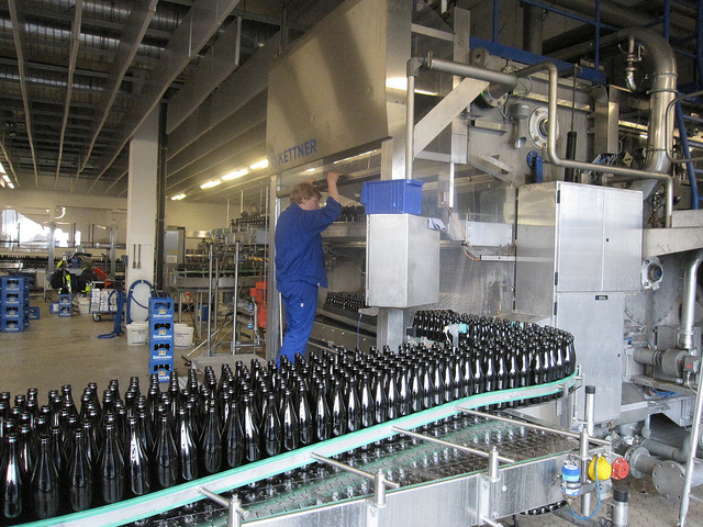 Man in blue uniform working at bottling plant.
