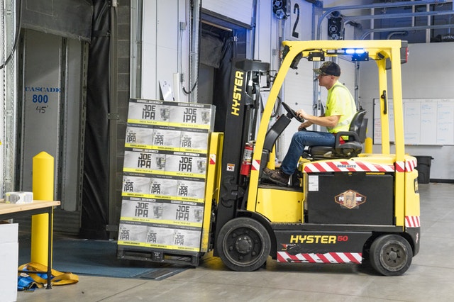 Yellow forklift lifting boxes.