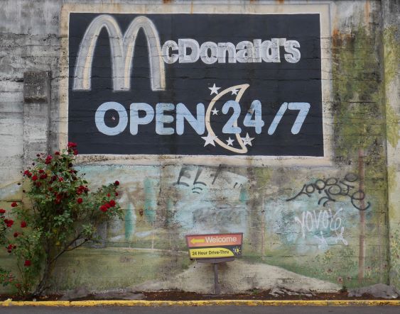 McDonald's sign painted on concrete wall "McDonalds OPEN 24/7"