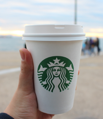 Supply Chain Scene, image of a hand holding a starbucks cup at the beach 