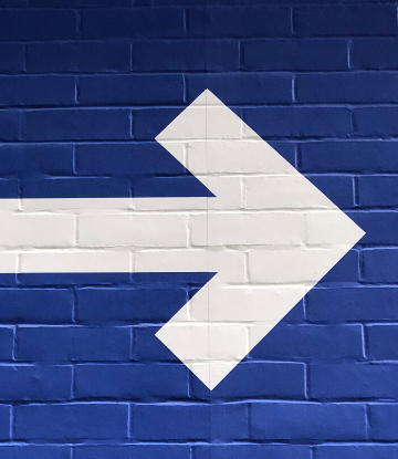 Supply Chain Scene, image of a white arrow painted on a blue wall