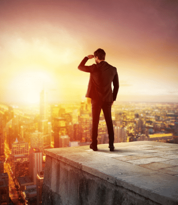 Image of a man standing on top of a building looking toward the sun