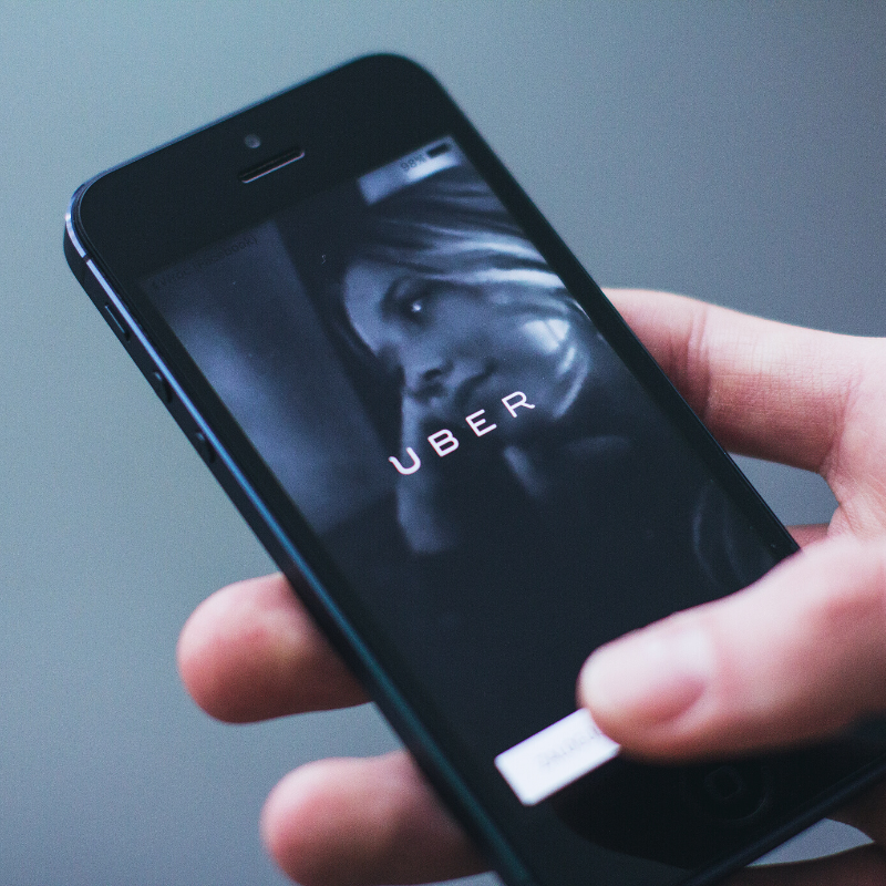 Image of a hand holding a smart phone using the Uber App 