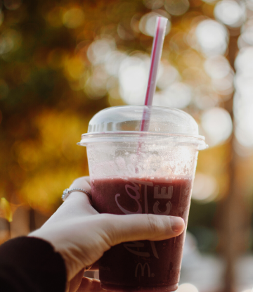 SCS, image of a hand holding a plastic coffee drink cup with straw 