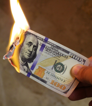 SCS, image of a hand holding a $100 bill that is on fire 