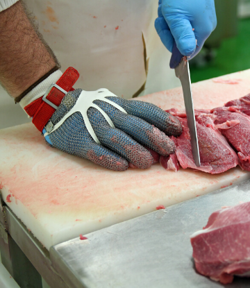 SCS, image of a meat processor cutting meat on a board 