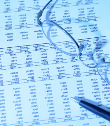 Image of a complex paper budget with glasses and a pen on top 
