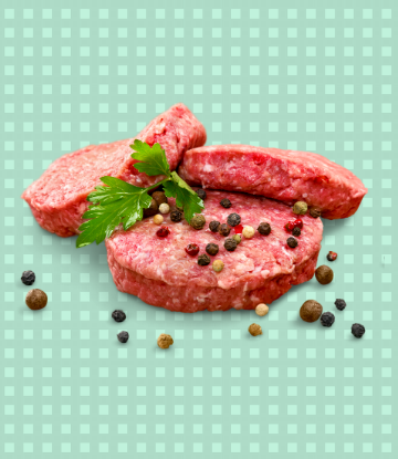 Image of raw hamburgers stacked, with fresh peppercorns