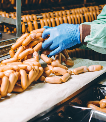 Image of worker processing sausages in a plant