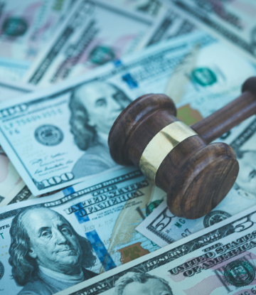 Image of a pile of money with a judge's gavel on top