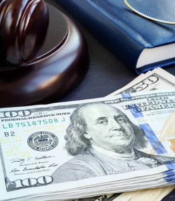 Image of a stack of money next to a court gavel and a law book 
