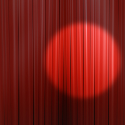 Image of a spotlight against a red stage curtain 