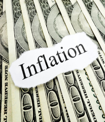 The word "inflation" on top of a stack of $100 bills 