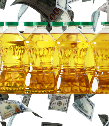 bottles of palm oil in front of falling money 